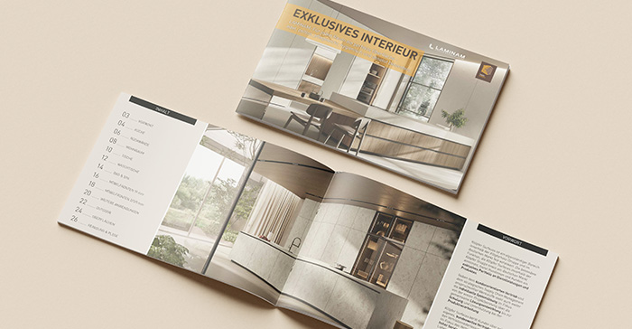 Die Laminam-Broschüre 'Exklusives Interior' liegt einmal geschlossen und einmal aufgeschlagen auf einem beigefarbenen Untergrund